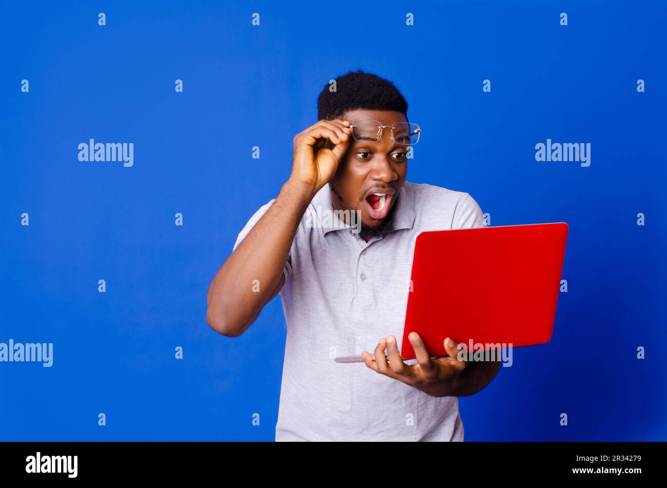 Young African man looking at the laptop surprisingly, isolated on a blue background Stock Photo