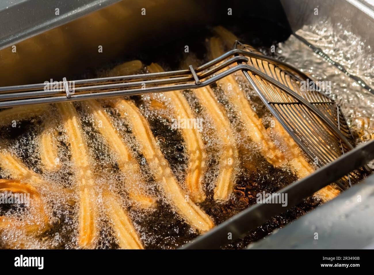 Process of cooking churros in boiling oil at street food market close