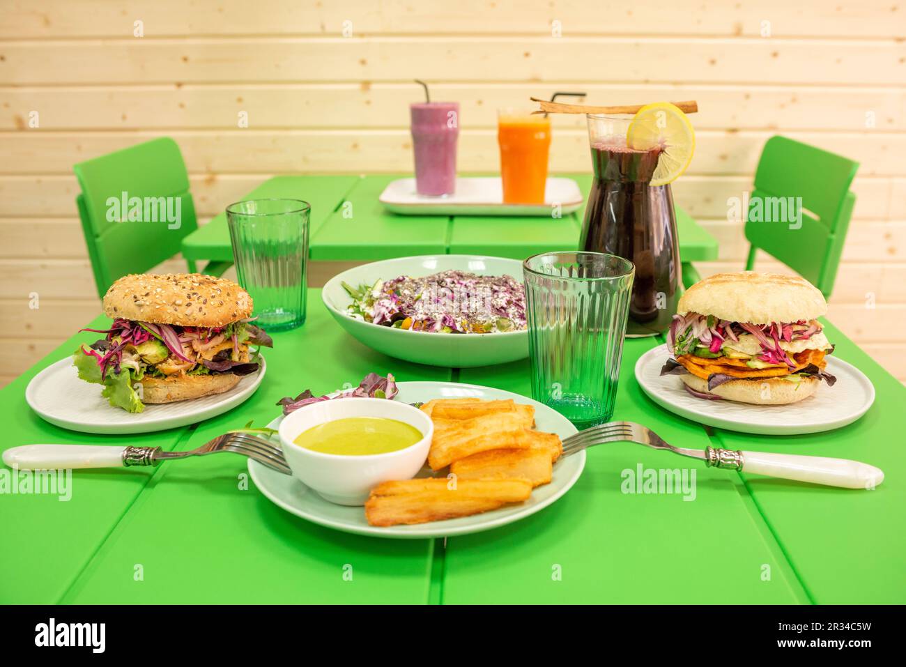 A bright green restaurant table with a set of Peruvian food dishes with cassava, vegetable burgers and chicha morada juice Stock Photo