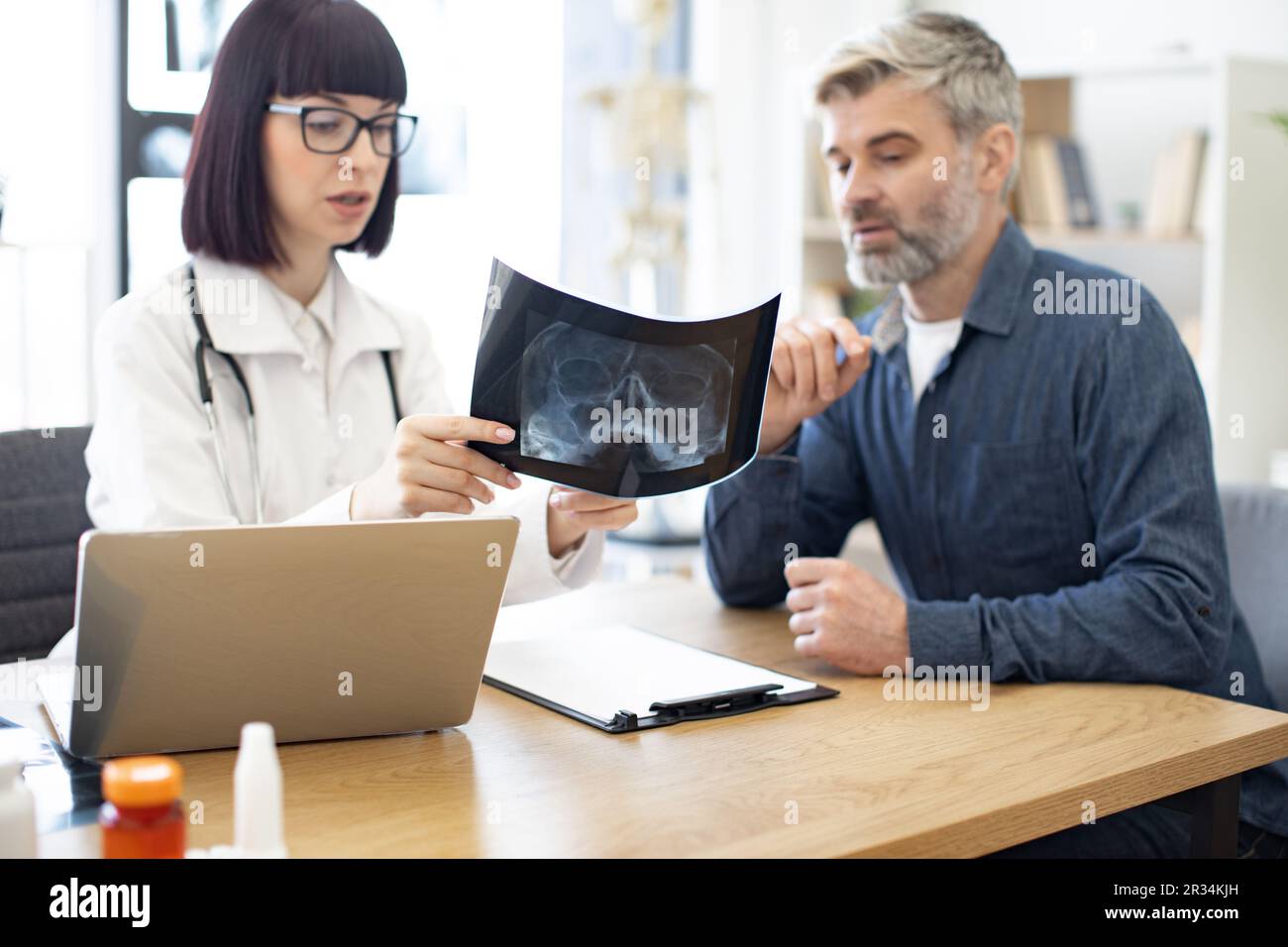 Skilled radiologist in white uniform and eyeglasses explaining visible ...