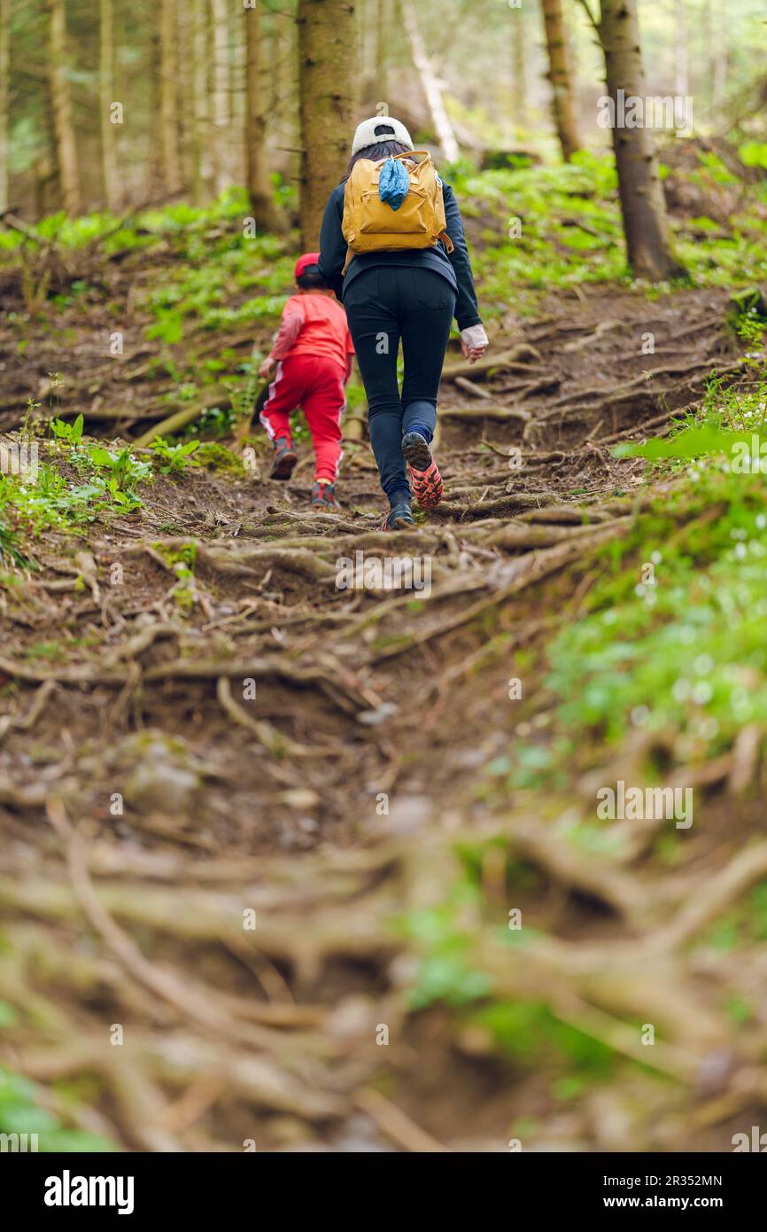 Mother and son climbing up a hiking trail in a mountain Stock Photo