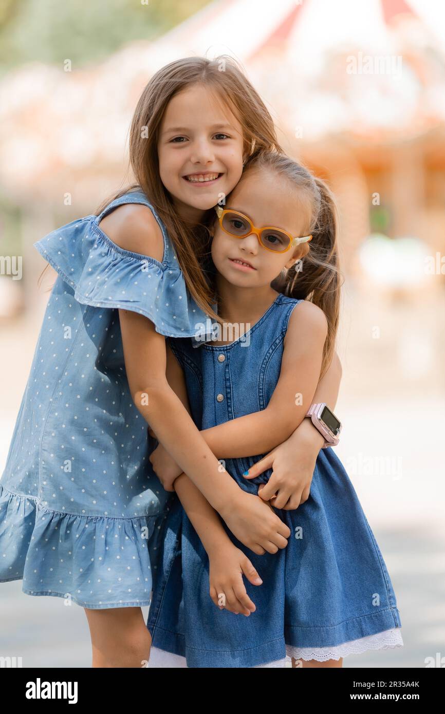 two little girls are happily walking in the amusement park in the summer. International Children's Day. A child with down syndrome. High quality photo Stock Photo