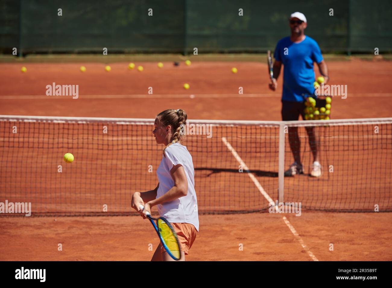 A professional tennis player and her coach training on a sunny day at