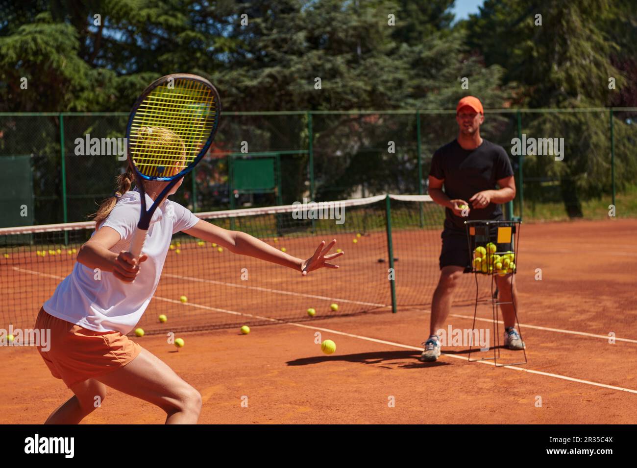 A professional tennis player and her coach training on a sunny day at