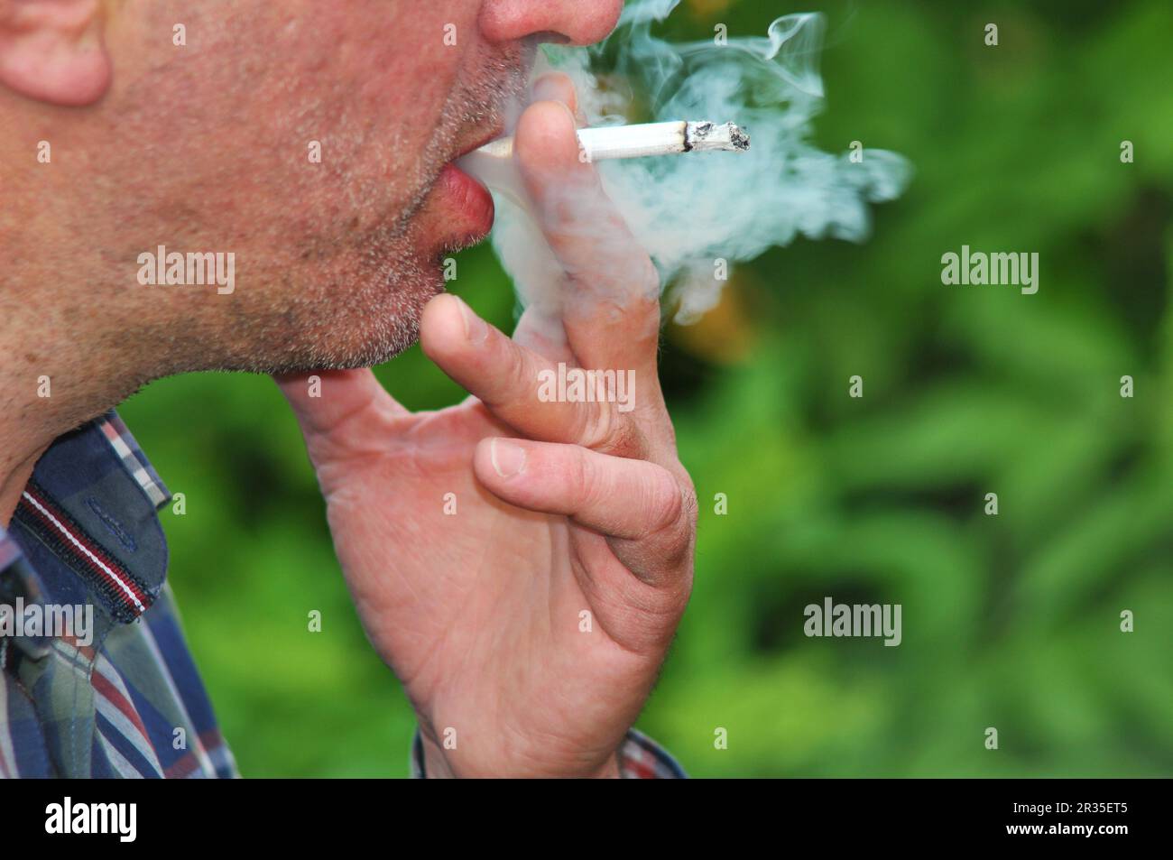 Young man smoking cigarette with pleasure outside Stock Photo
