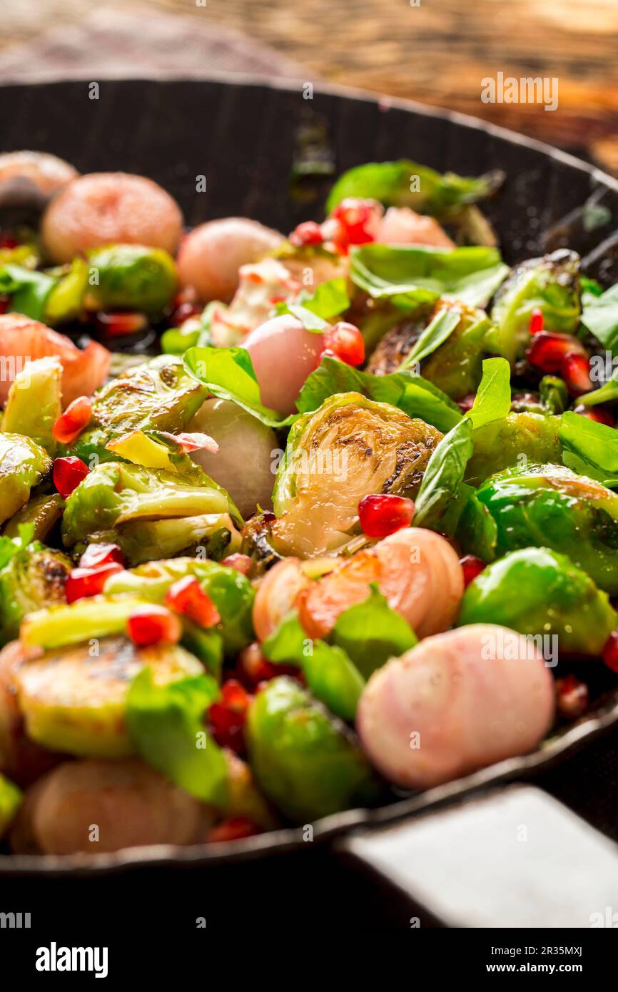 Fried Brussels sprouts with basil, onions and pomegranate seeds Stock Photo