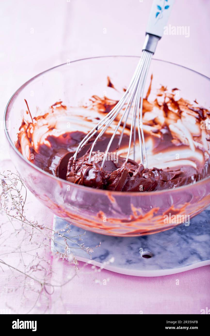 Chocolate icing in a mixing bowl with an egg whisk Stock Photo