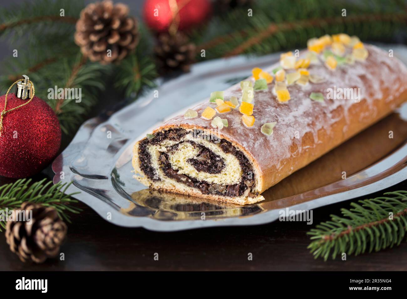 Traditional poppy seed roll cake with icing, dried fruits and nuts (Poland) Stock Photo