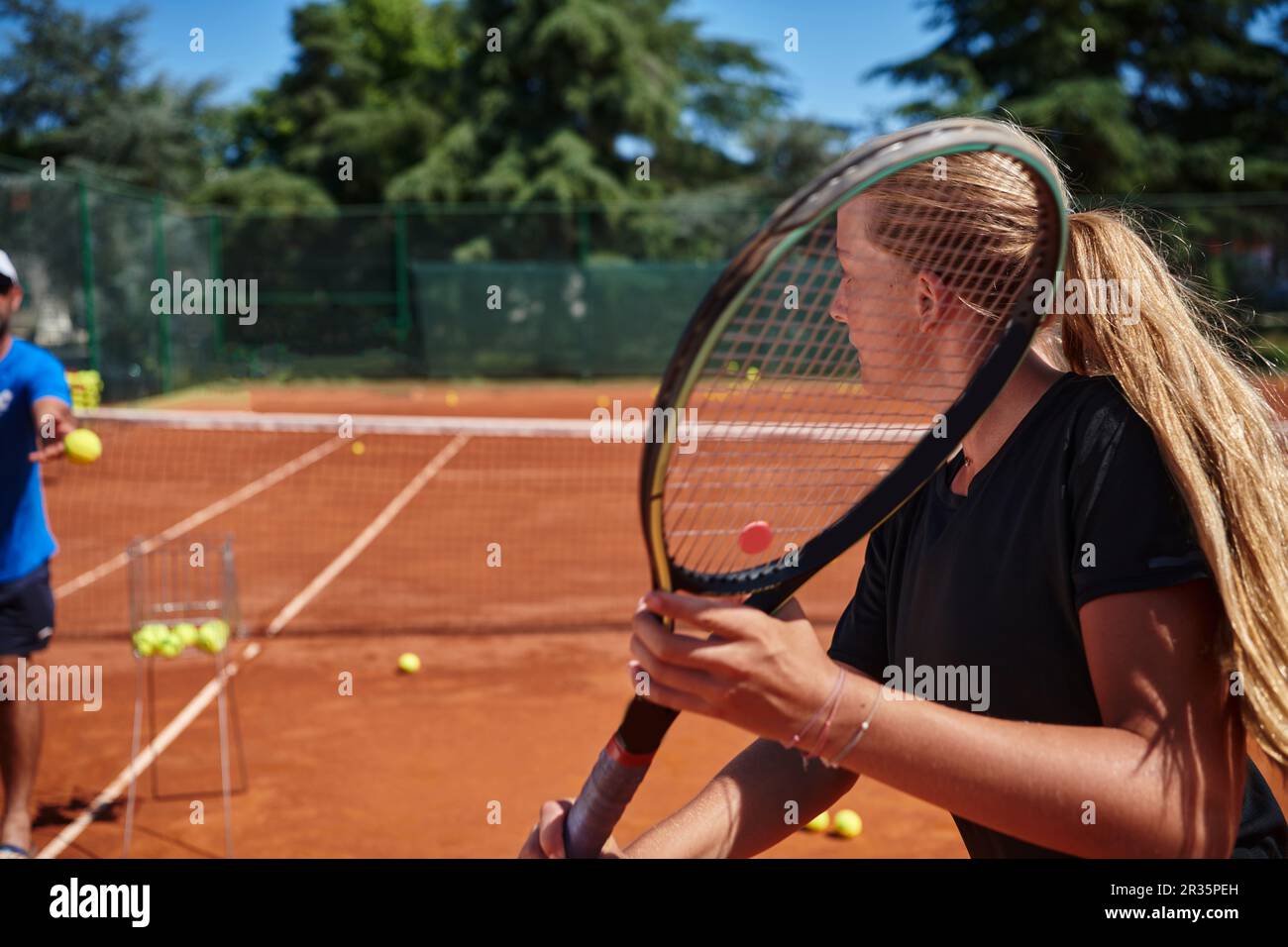 A professional tennis player and her coach training on a sunny day at