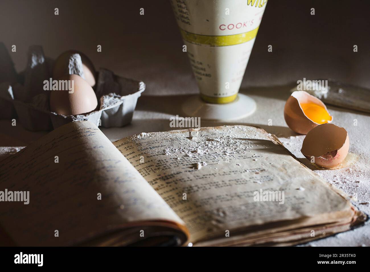 A baking scene with and old recipe book, eggs and flour Stock Photo