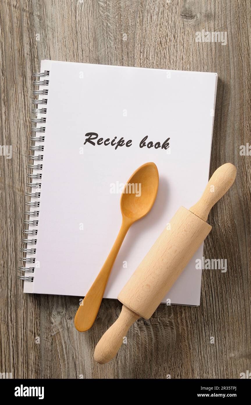 A recipe book, a wooden spoon and a rolling pin Stock Photo