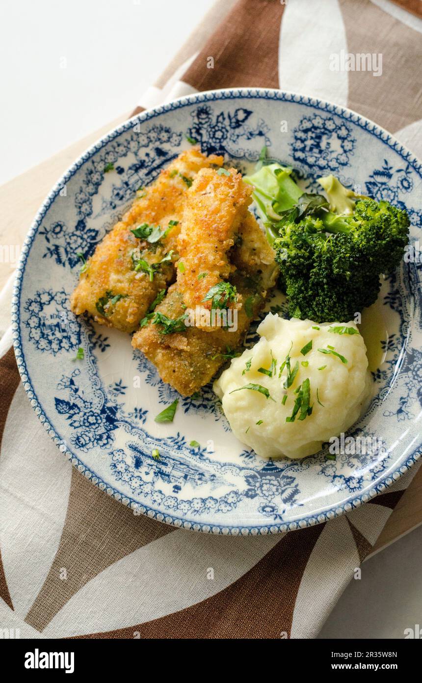 Breaded fish fillets with broccoli and mashed potatoes Stock Photo