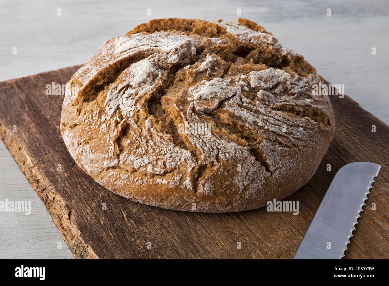 Country bread on a wooden board with a bread knife Stock Photo