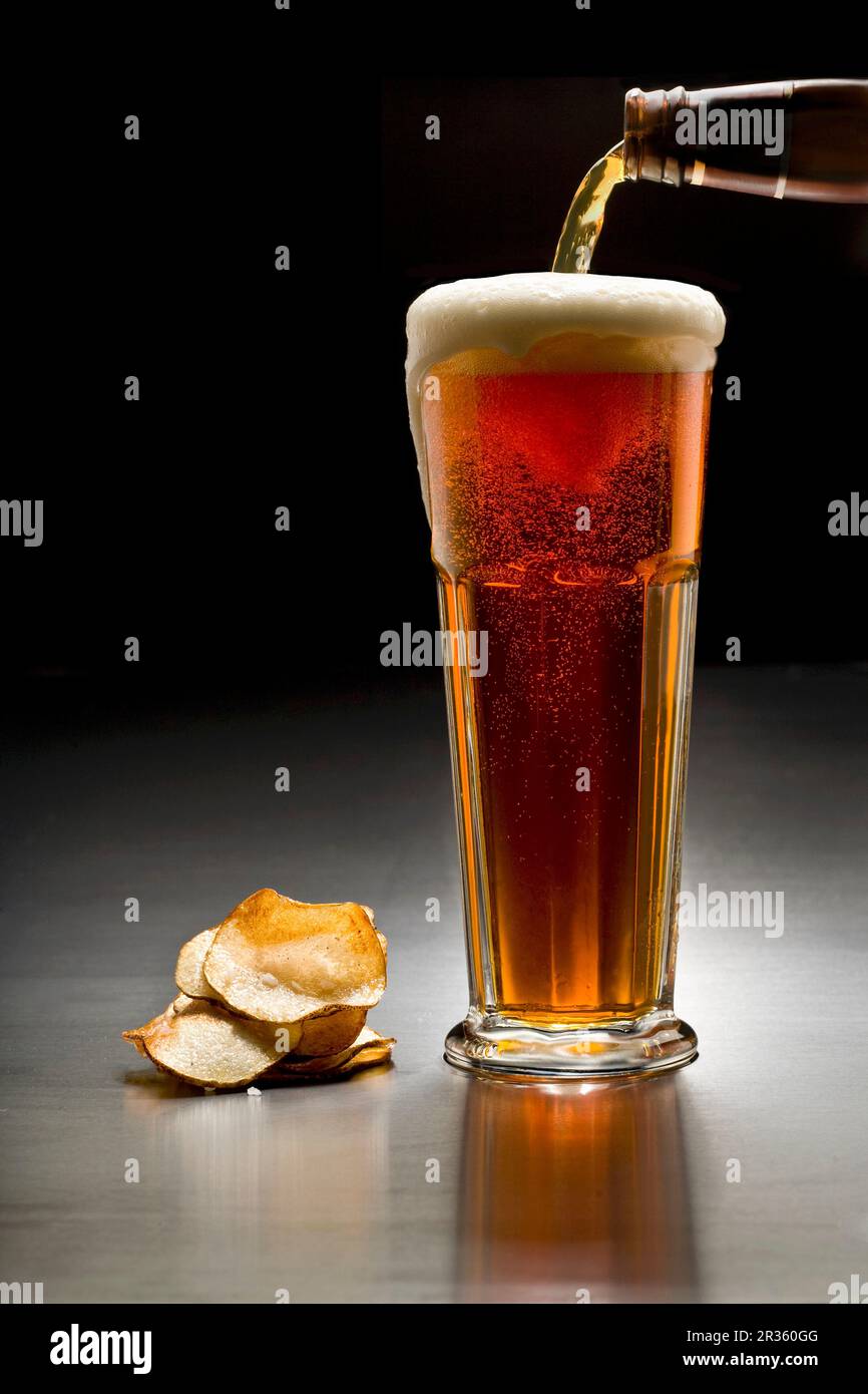 A glass of dark beer and crisps Stock Photo Alamy
