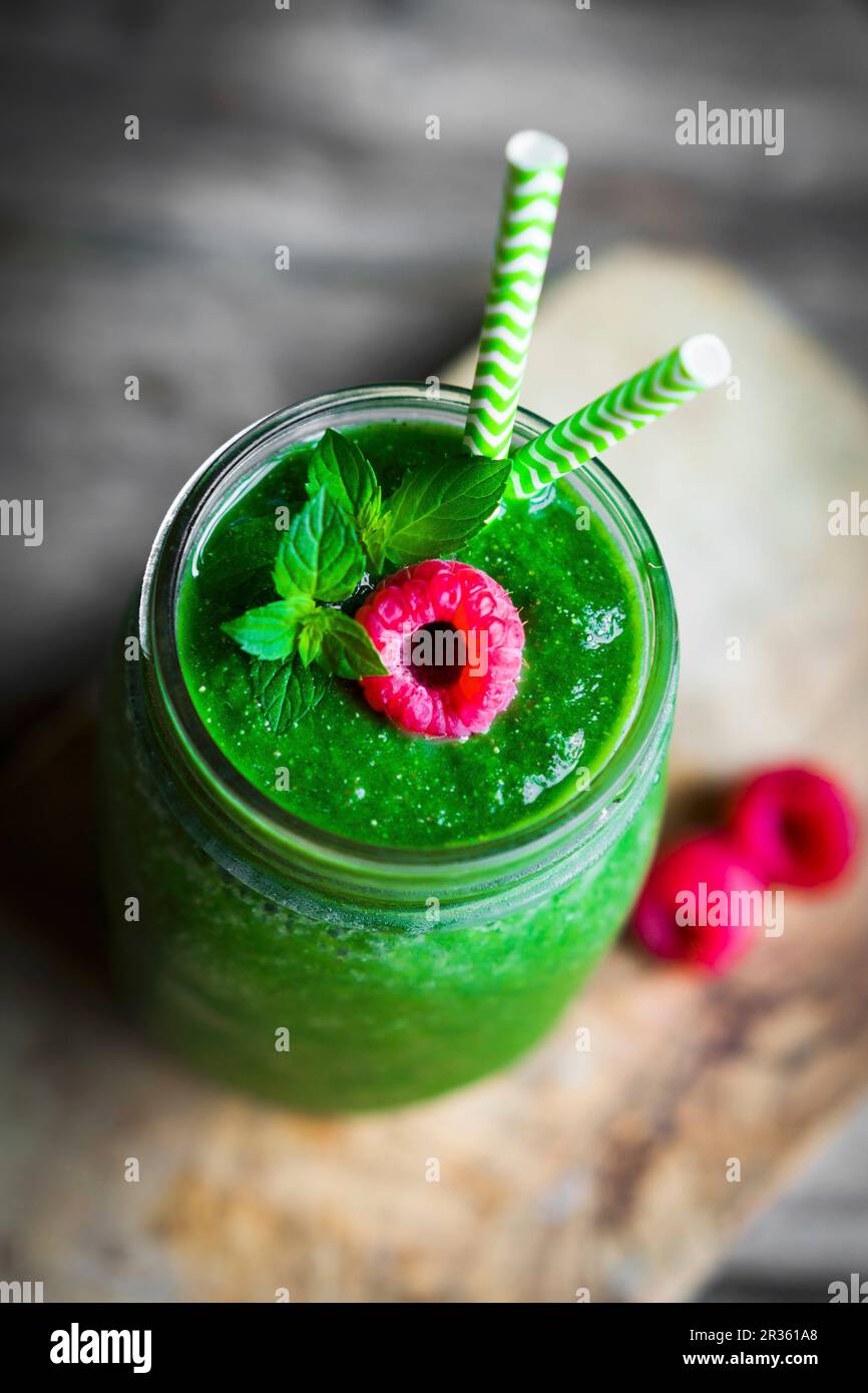 A green smoothie garnished with a raspberry Stock Photo