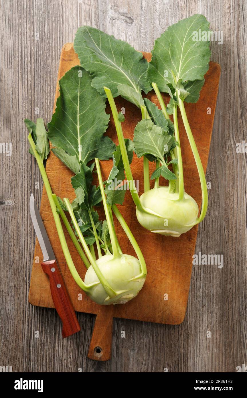 Two fresh kohlrabi on a wooden chopping board (seen from above) Stock Photo