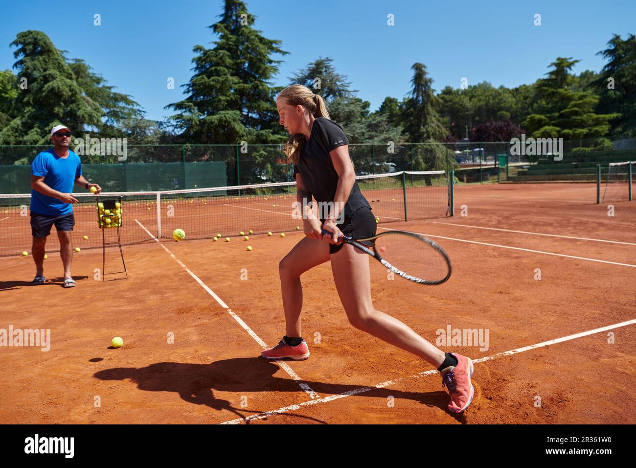 A professional tennis player and her coach training on a sunny day at