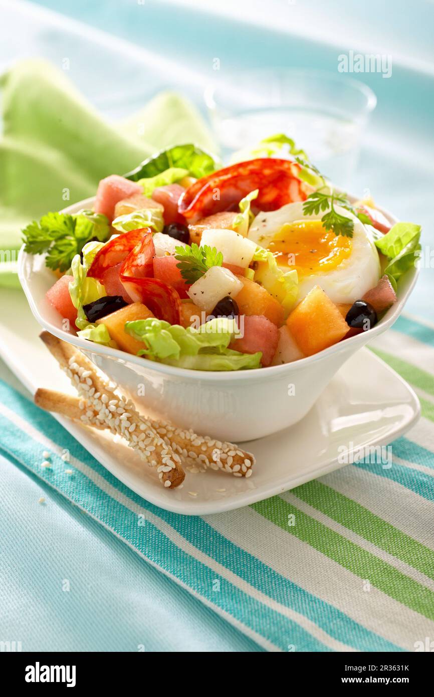 Salad with salami, half an egg, melon and olives Stock Photo