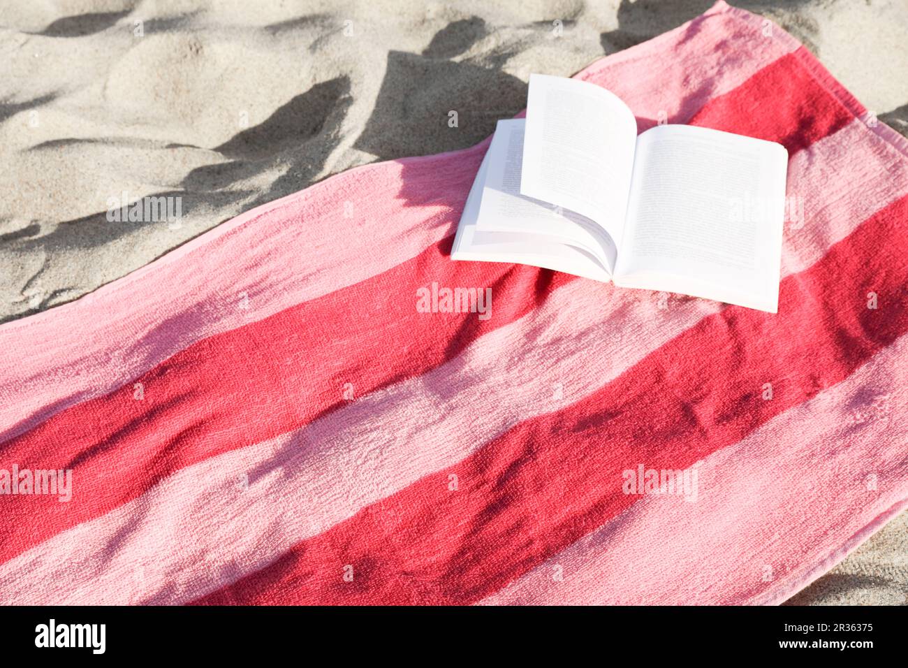 Beach towel and open book on sand Stock Photo - Alamy