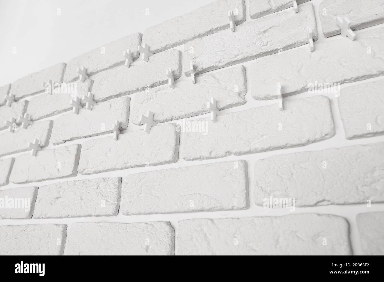 Decorative white bricks with tile leveling system on wall Stock Photo
