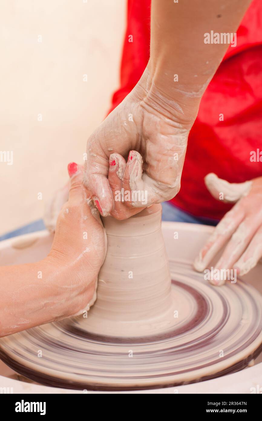 Hands of girl who tries to make pottery from white clay on a potter's