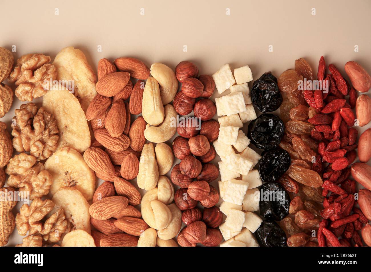 Different tasty nuts and dried fruits on beige background, flat lay ...