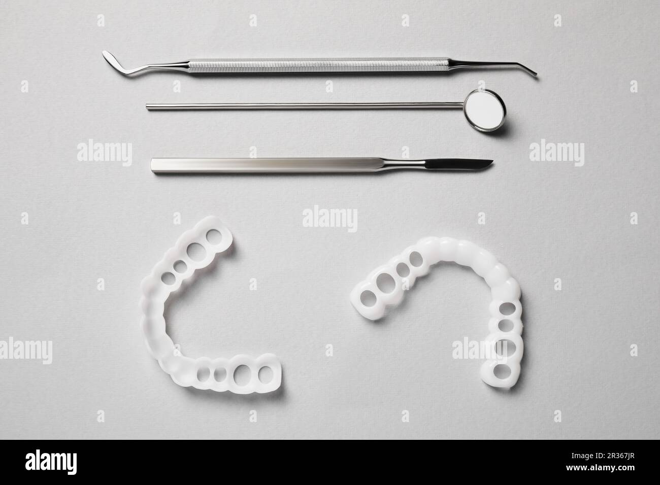 Bite correction. Mouth guards and dentist tools on light grey background, flat lay Stock Photo