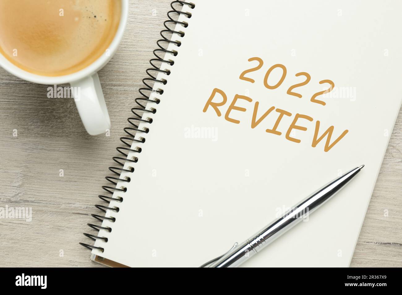 Text 2022 Review written in notebook, pen and cup of coffee on wooden table, top view Stock Photo