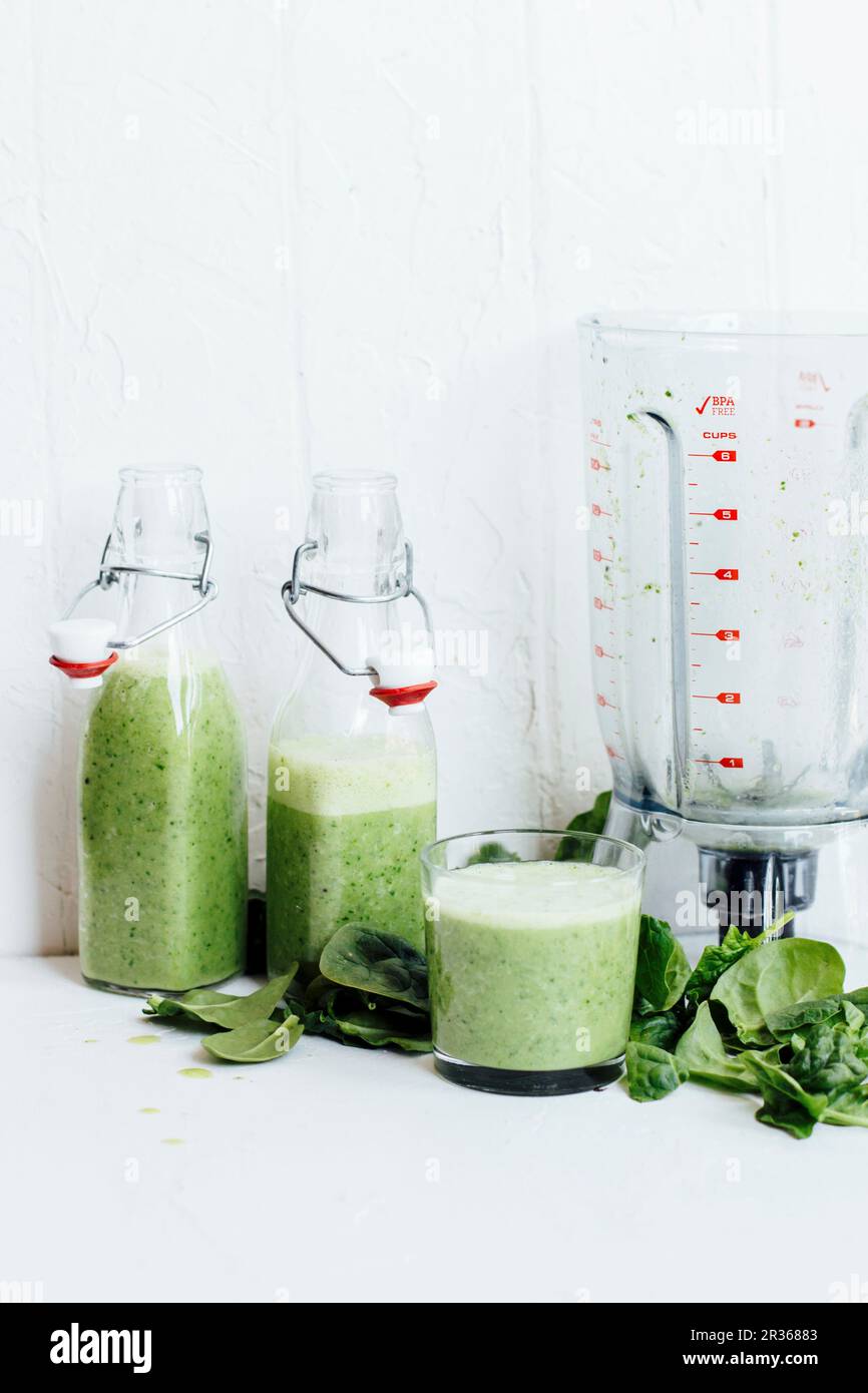 Green smoothies, spinach leaves and a blender Stock Photo