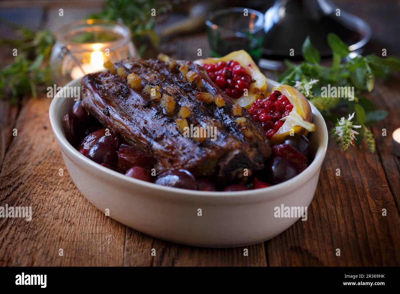 Studded roast venison with plums and lingonberry pears Stock Photo