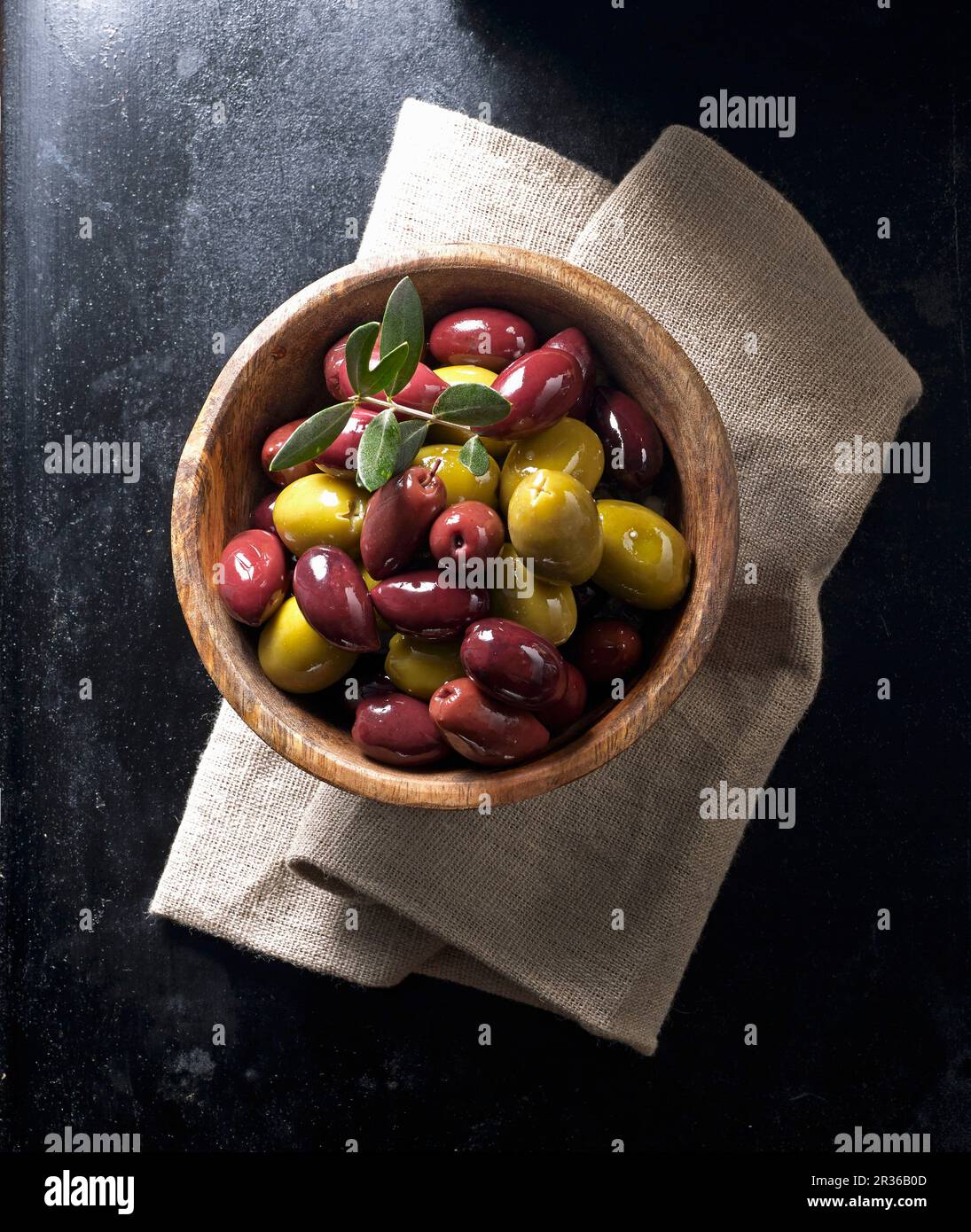 Kalamata olives and green olives in a wooden bowl on a linen napkin Stock Photo