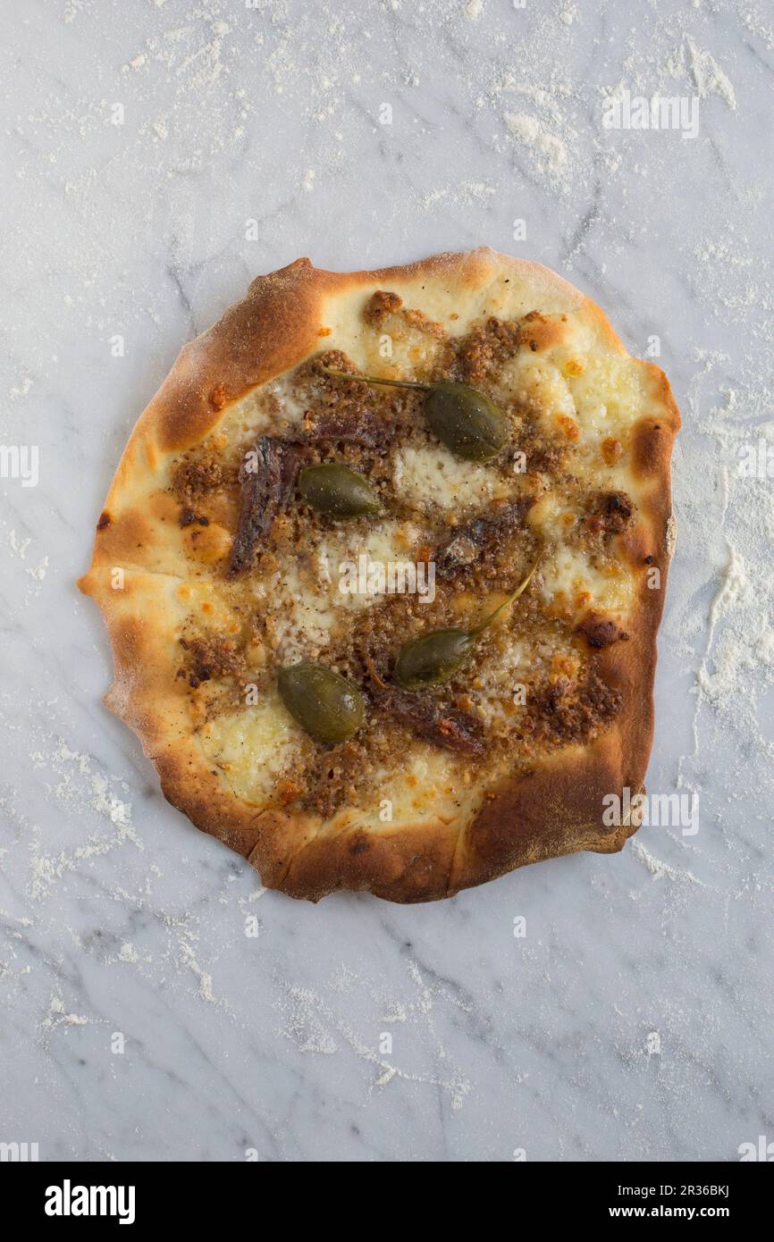 Homemade pizza with mozzarella, caper fruits, walnut pesto and lemon