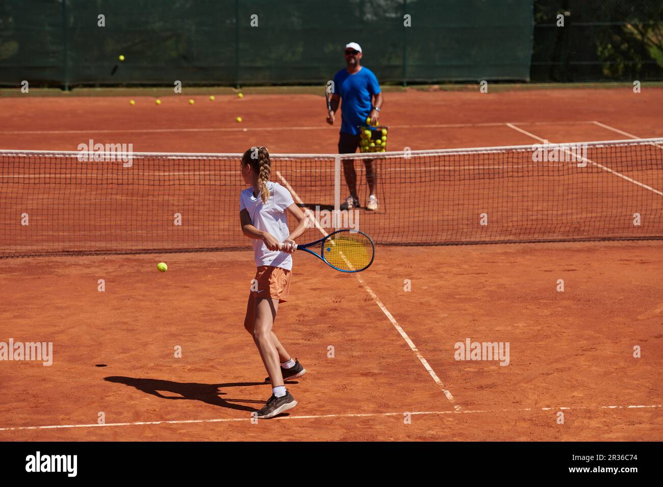 A professional tennis player and her coach training on a sunny day at