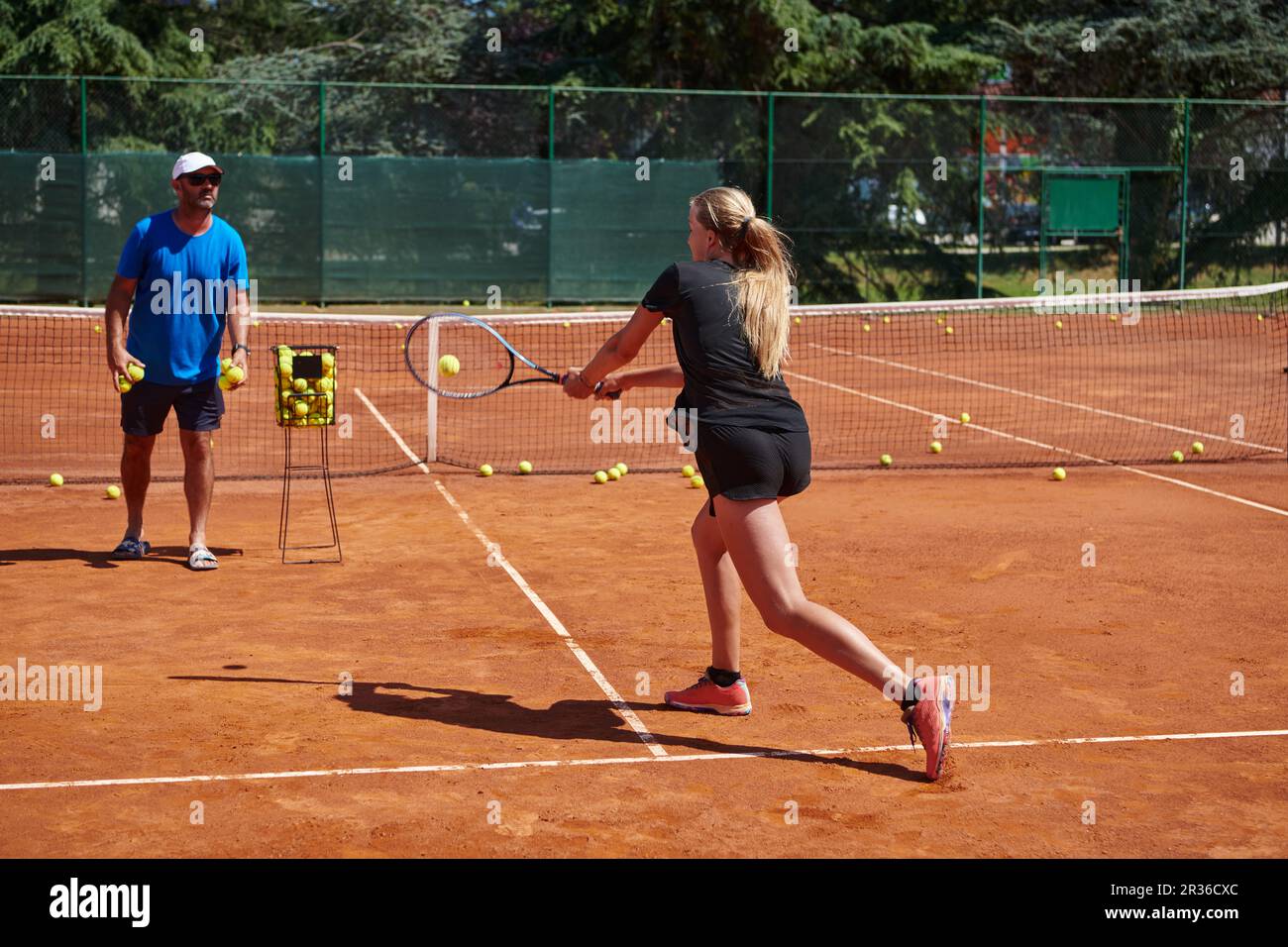 A professional tennis player and her coach training on a sunny day at