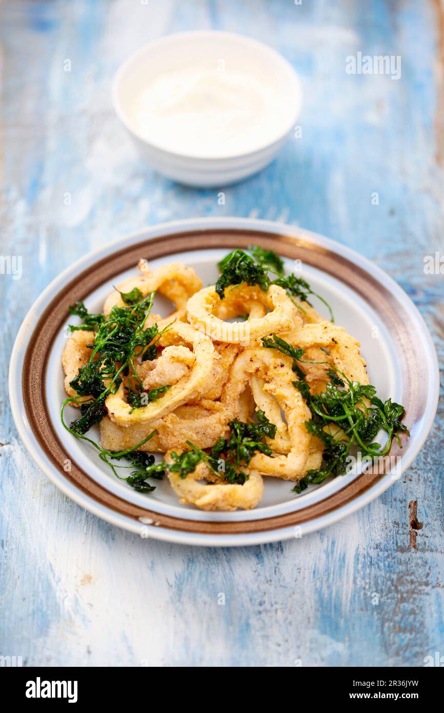 Baked squid rings with fried parsley Stock Photo - Alamy