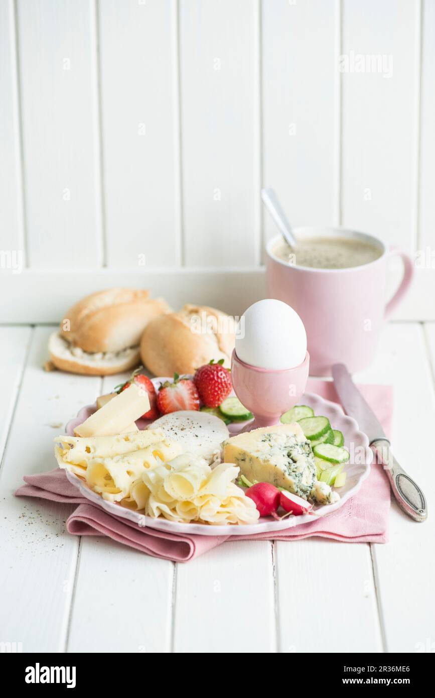 Cheese breakfast with an egg, radishes, strawberries, cucumber, bread rolls and coffee Stock Photo