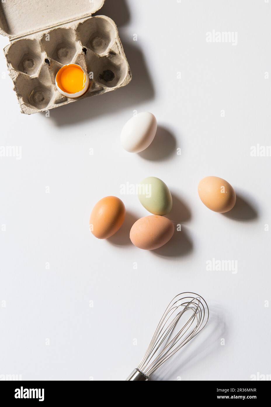 Fresh chicken eggs next to an egg box with a cracked open egg Stock Photo