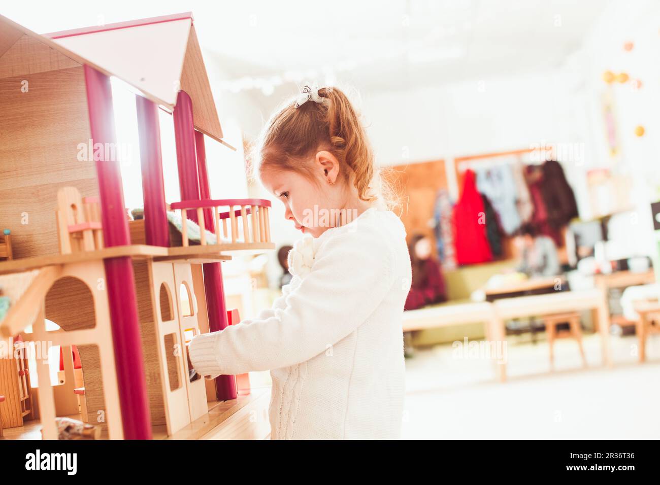 Girl playing with a dollhouse Stock Photo - Alamy