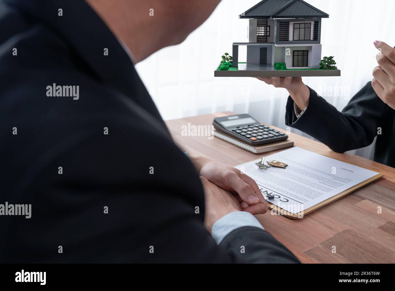 Client and real estate agent review loan contract, discussing term, interest rate, and property
