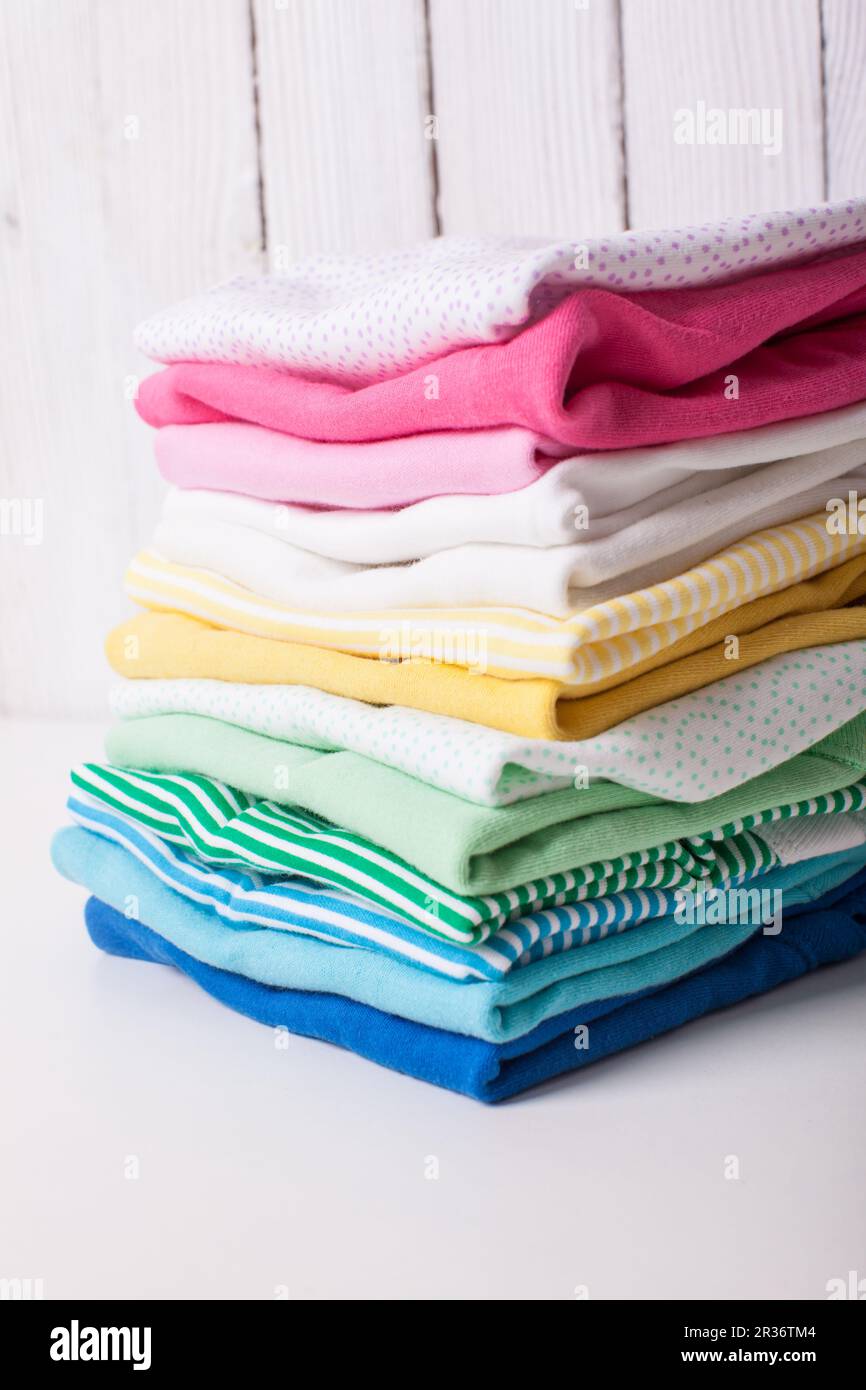 Colorful baby clothes of folded pile on a white background Stock Photo
