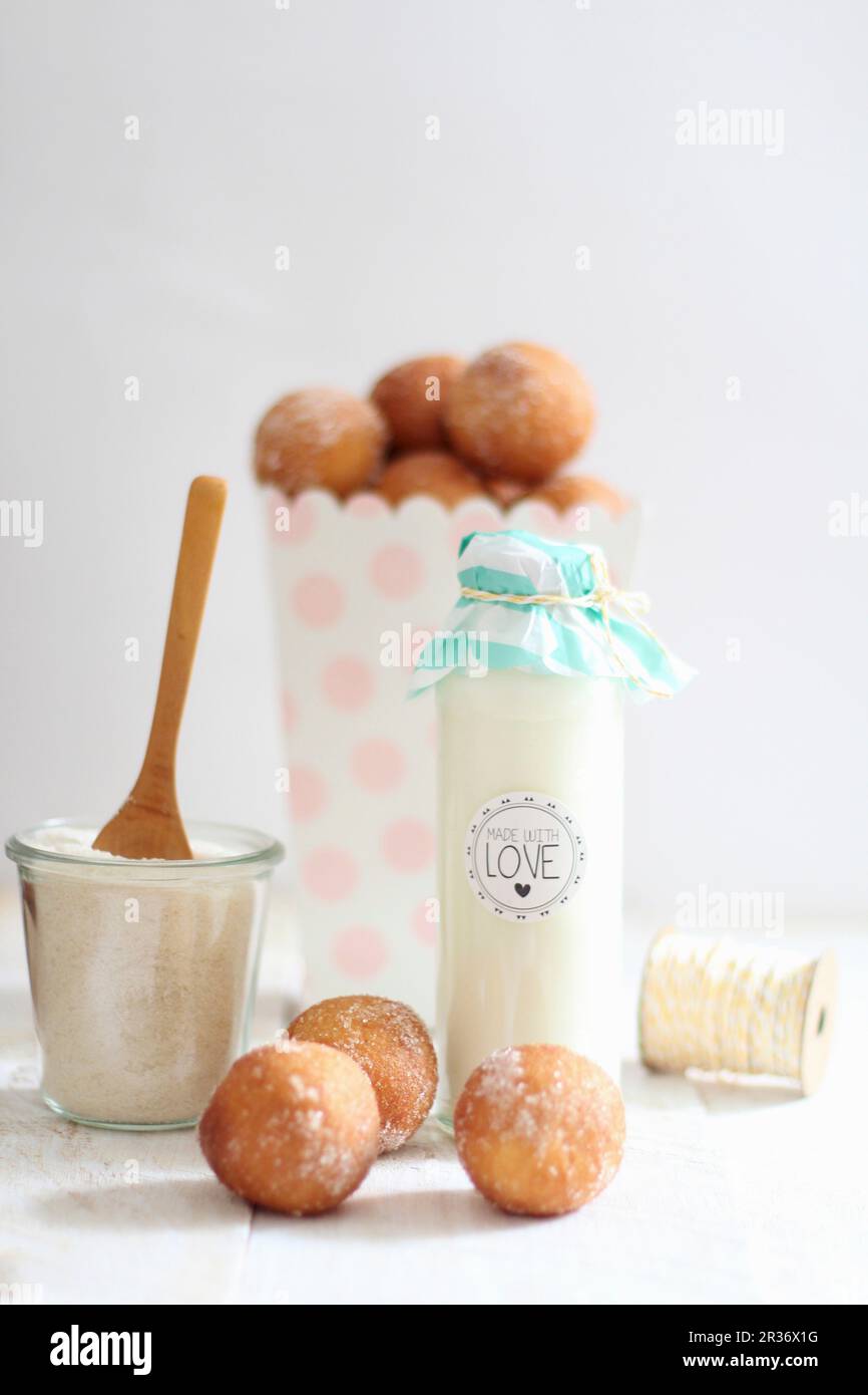 Milk in a decorative glass bottle and quark doughballs with cinnamon sugar Stock Photo