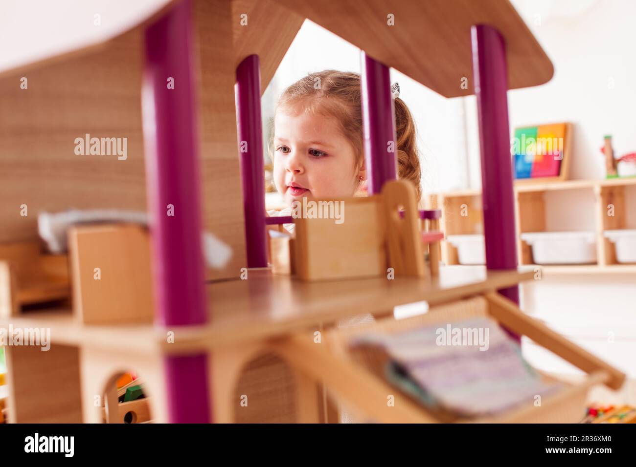 Girl playing with a dollhouse Stock Photo - Alamy