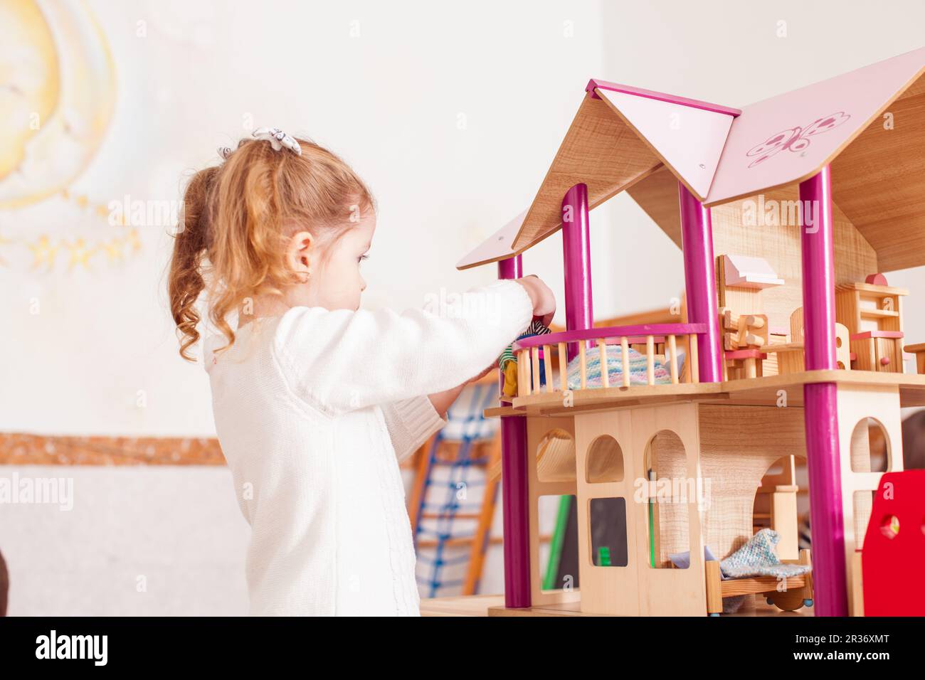 Girl playing with a dollhouse Stock Photo - Alamy