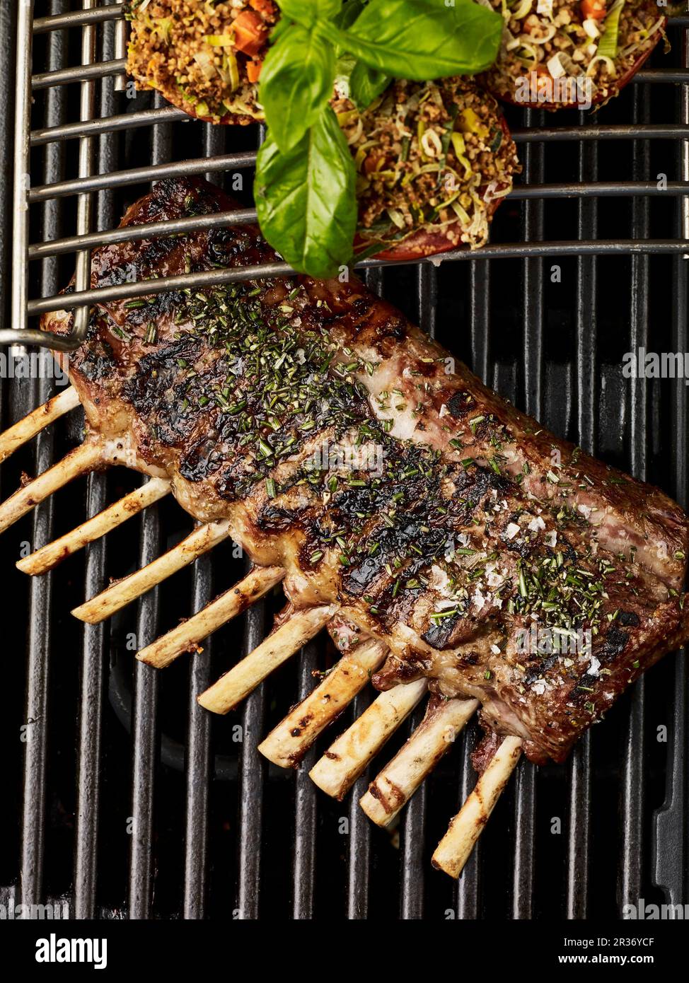 A rack of lamb with herbs and stuffed tomatoes on a barbecue Stock ...