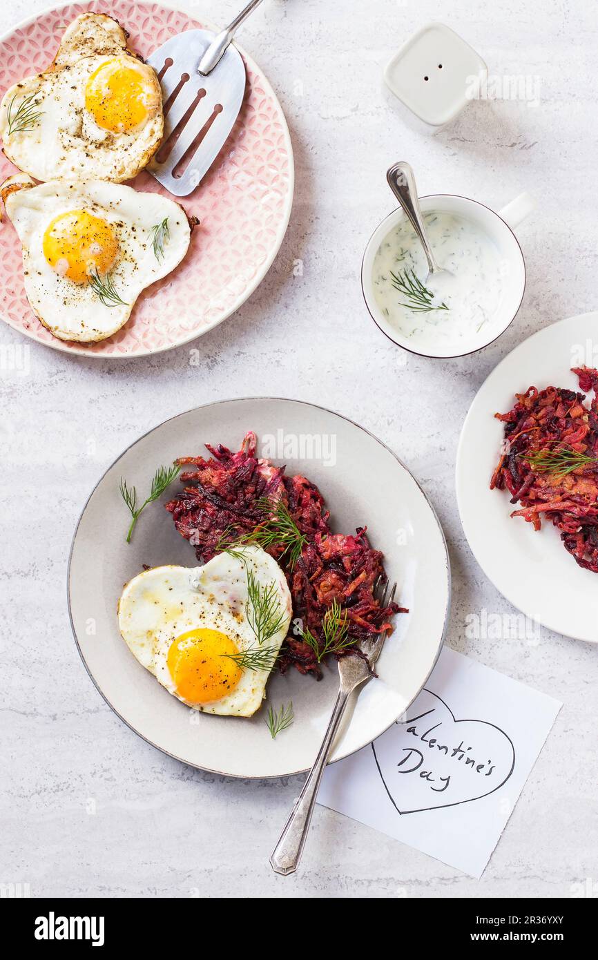 Beetroot and carrot fritters with heart-shaped fried eggs for Valentine's Day Stock Photo