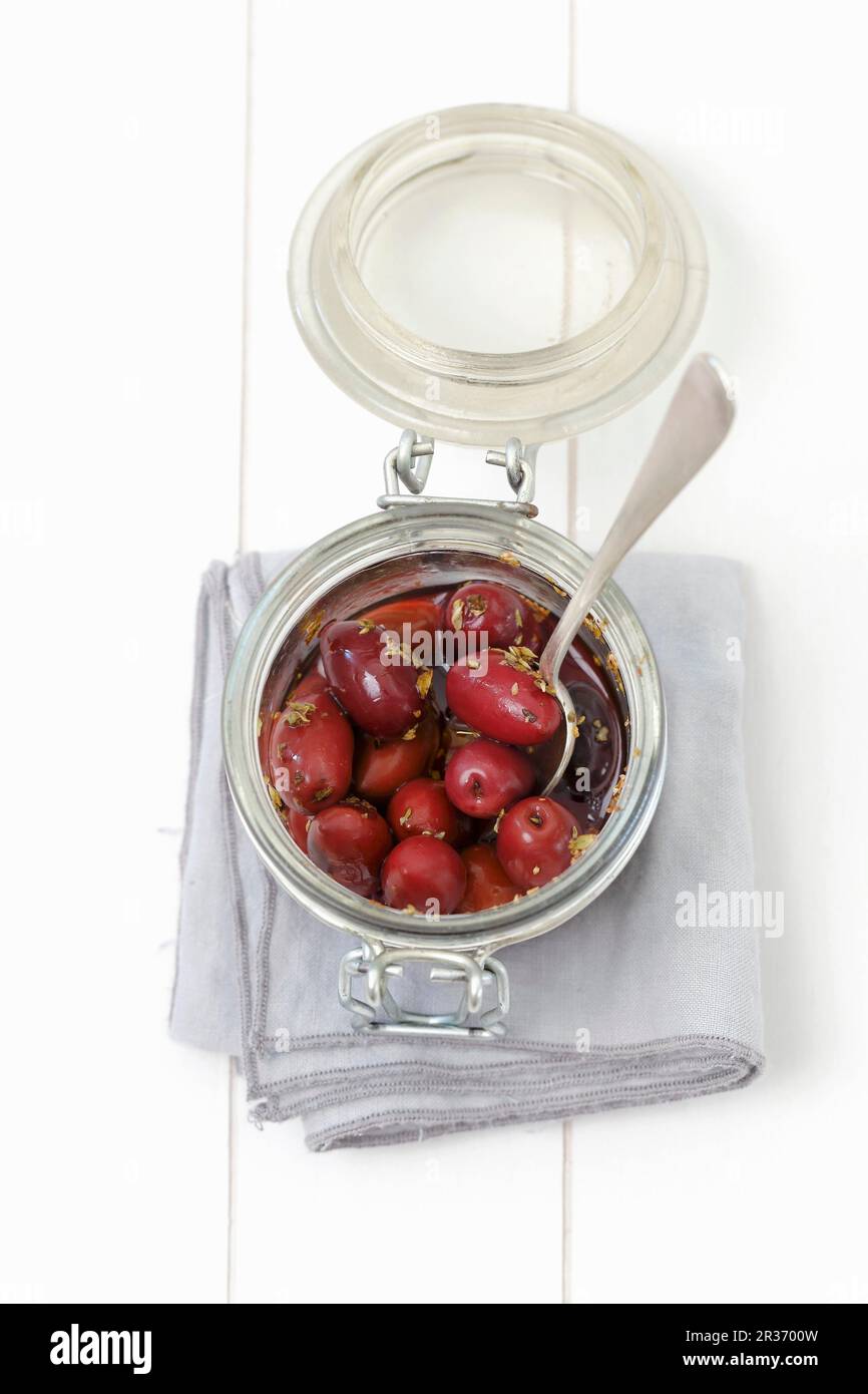 Pickled kalamata olives with oregano in a glass jar Stock Photo