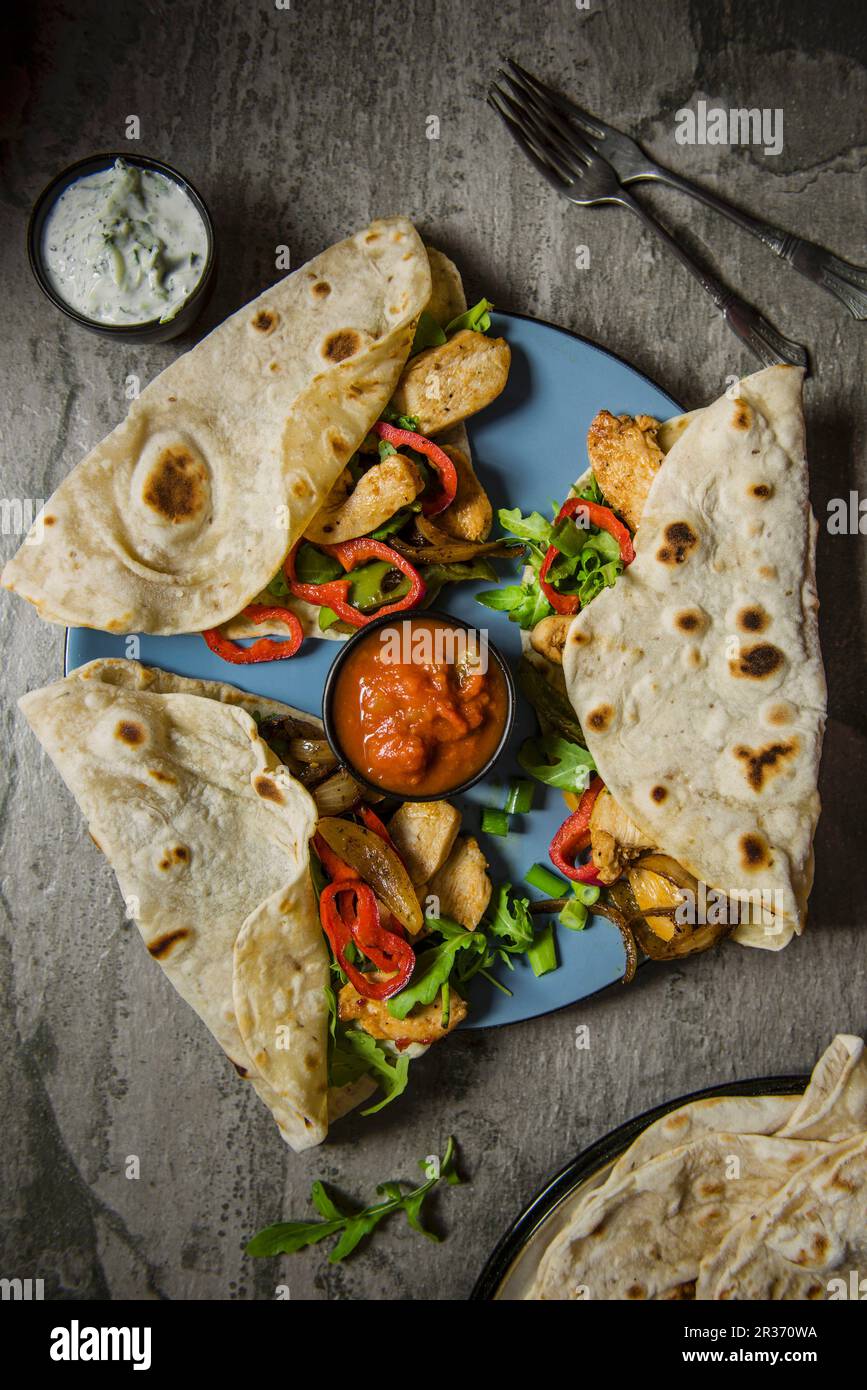 Tortilla wraps with spiced chicken, onion, peppers, salsa and a side
