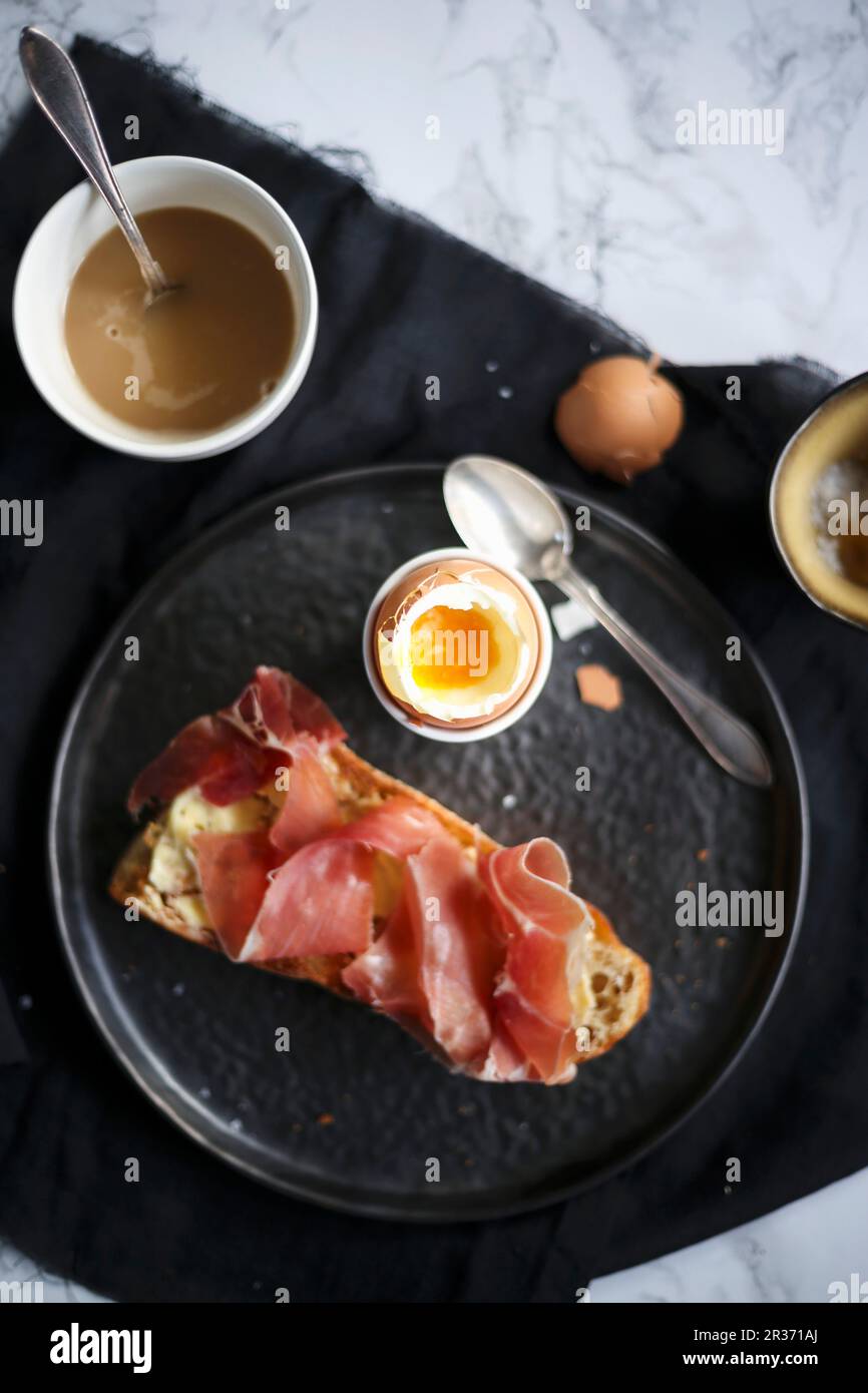 Breakfast with a soft-boiled egg and bread with ham Stock Photo