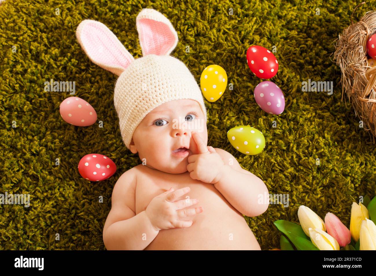 Three months baby lying on on the grass carpet as a Easter bunny Stock