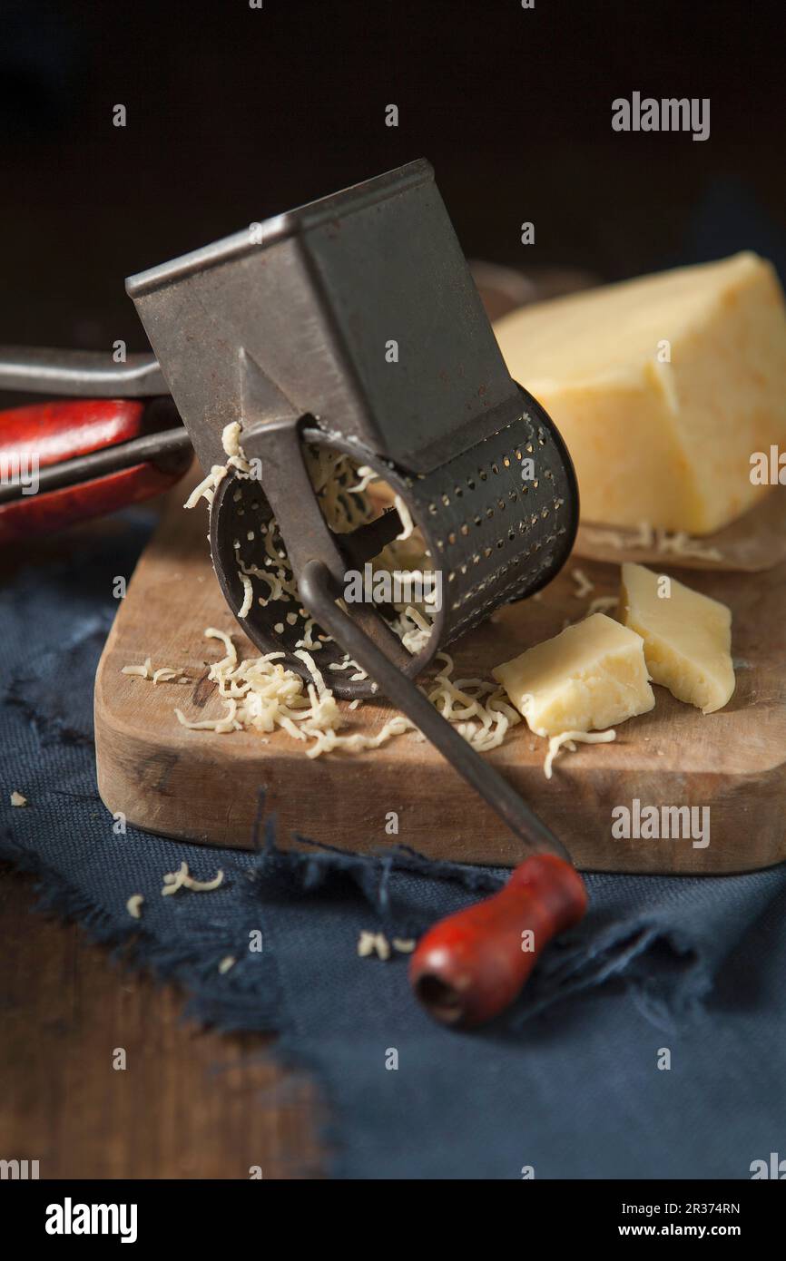 Cheddar cheese being grated by a Vintage rotary cheese grater Stock